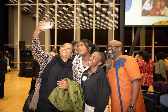 Olufemi “Femi” Ogundele, associate vice chancellor of enrollment and dean of undergraduate admissions (right), poses for a selfie with two scholars and a guest at the celebration