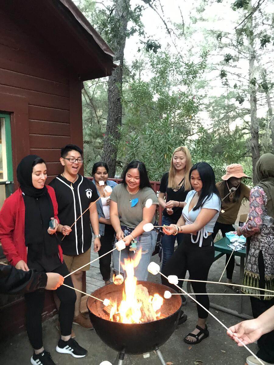 Students and staff making smores and smiling