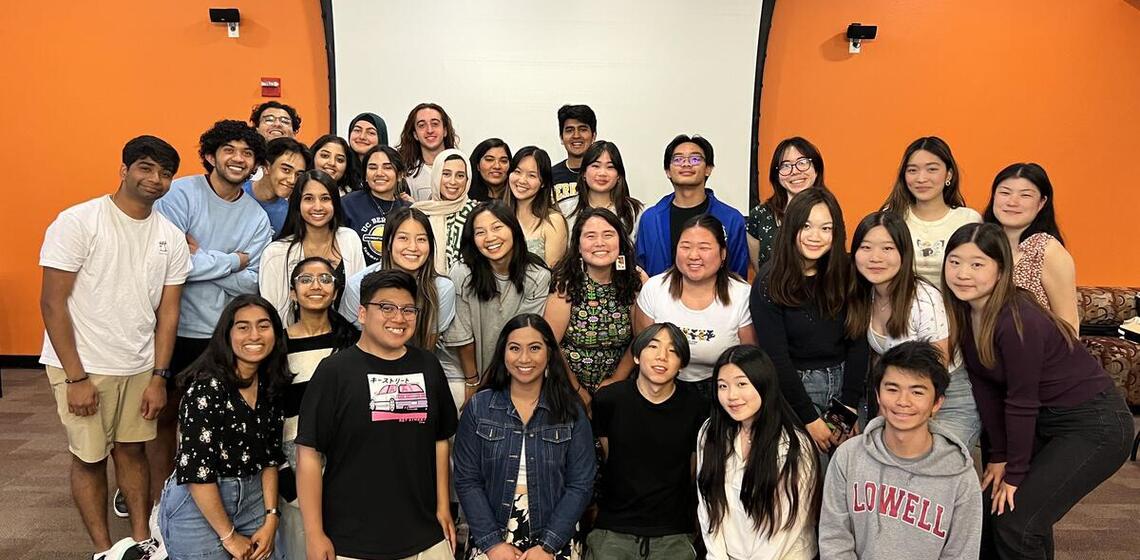 A big group of students in front of an orange wall