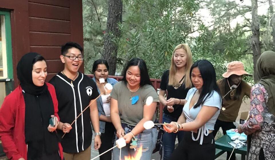 A group of students and staff around a campfire making smores